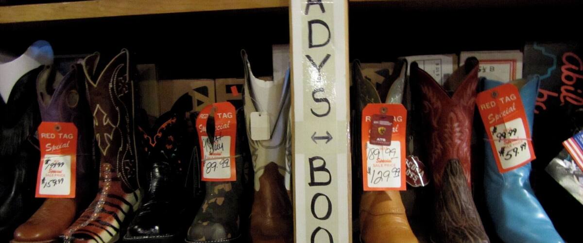 A variety of boots on shelves, with a sign indicating 'LADY BOOTS'.