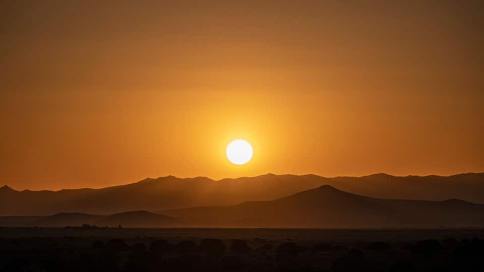A sunset over a mountain range with a clear sky.