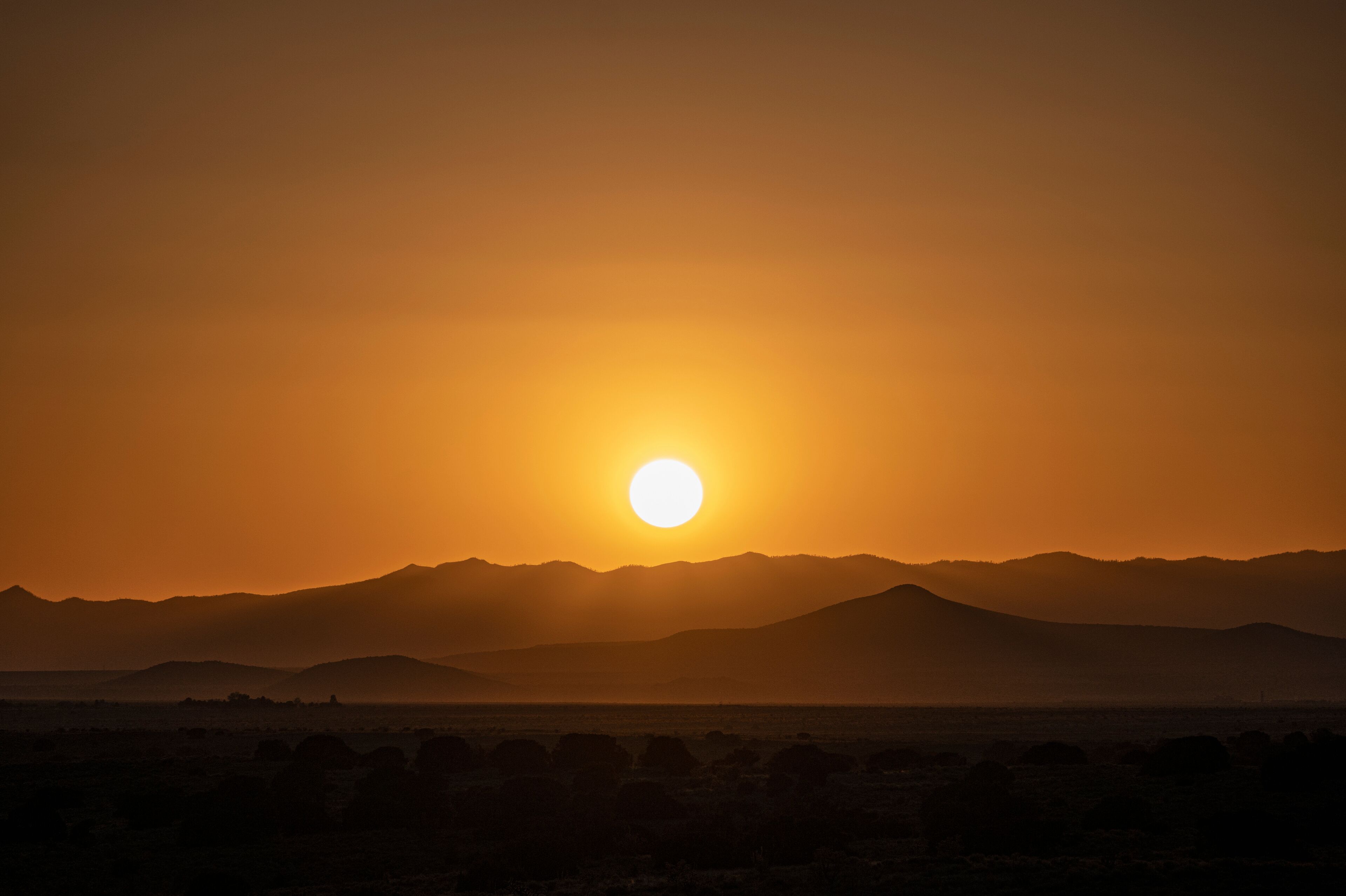 A sunset over a mountain range with a clear sky.