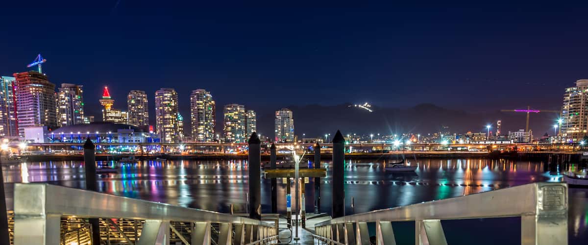 skyline of downtown Vancouver at night with mountains in background