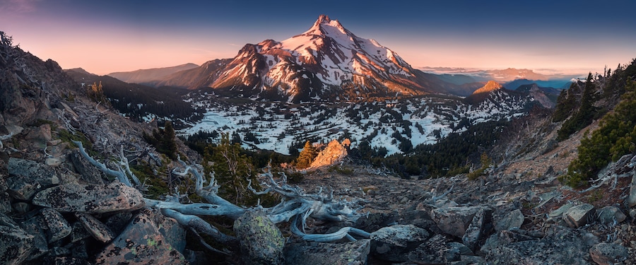 Une chaîne de montagnes aux sommets enneigés, avec une vallée en contrebas.