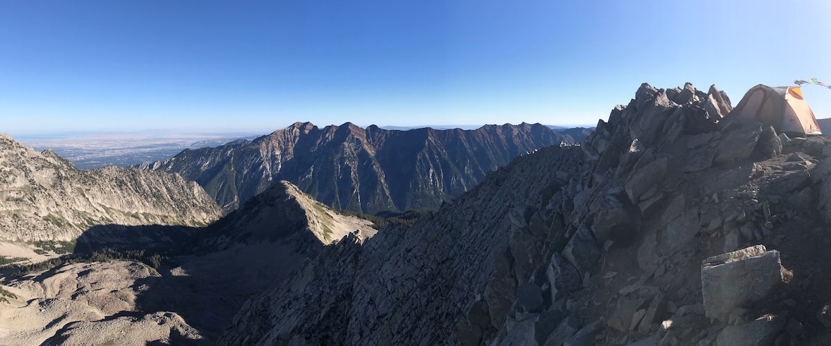 A mountain range with a tent on a rocky outcrop.