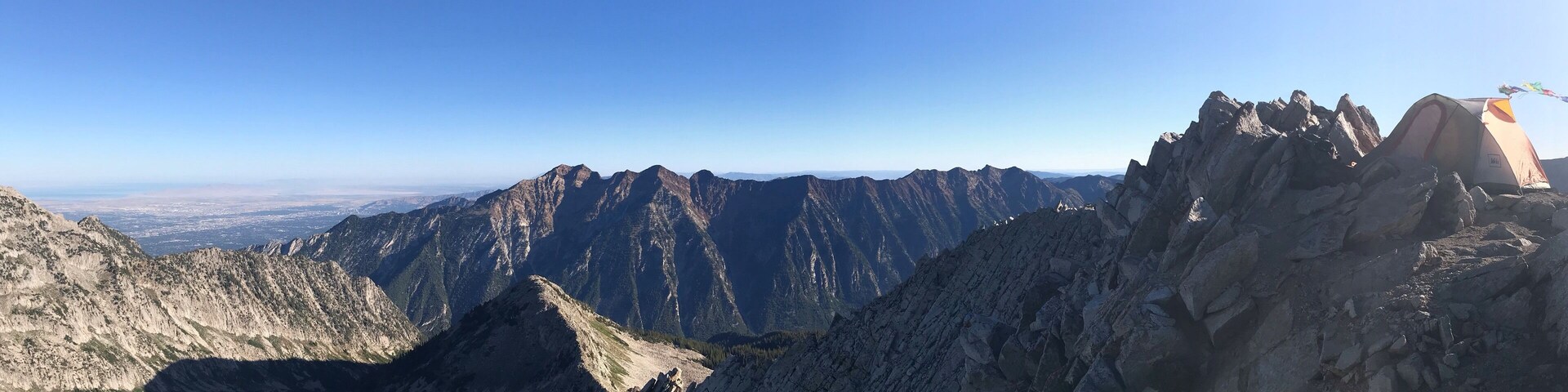 A mountain range with a tent on a rocky outcrop.