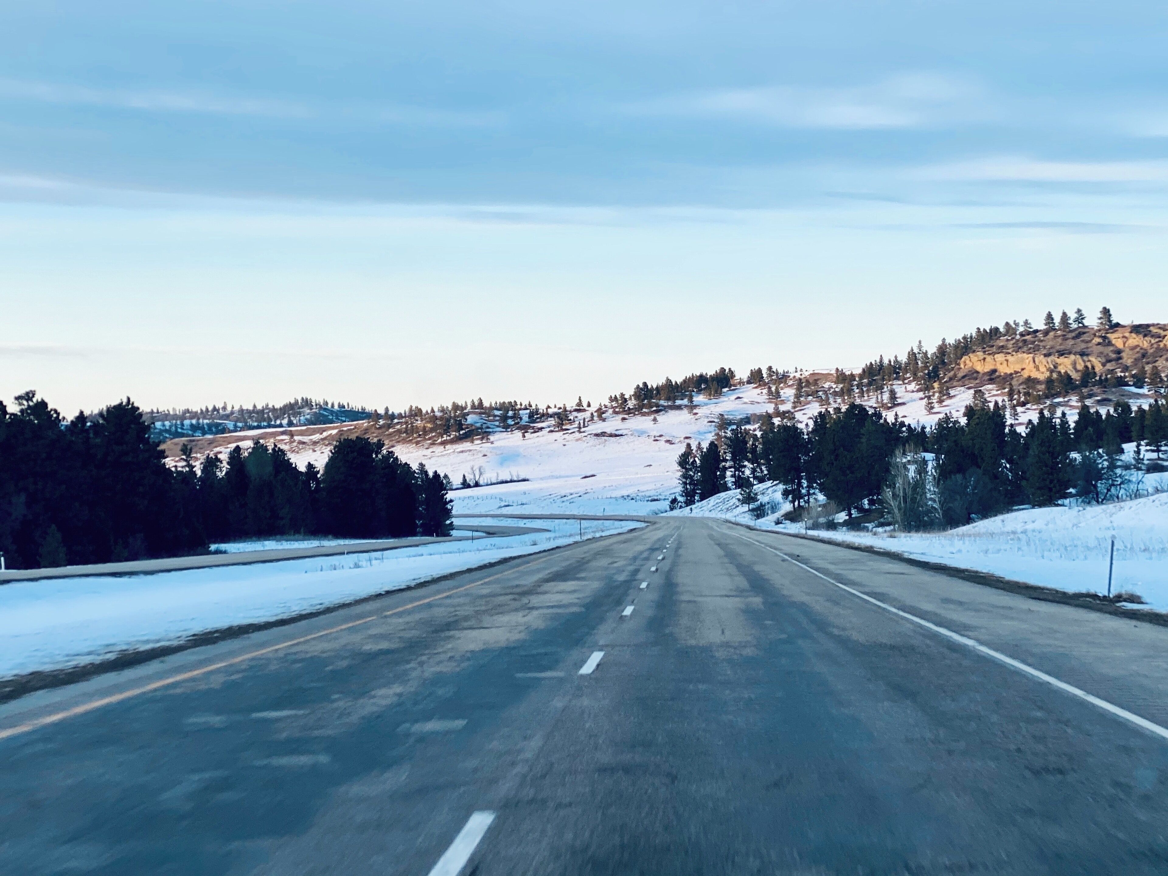 A snow-covered road with a clear sky and distant mountains.
