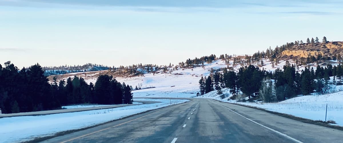 A snow-covered road with a clear sky and distant mountains.