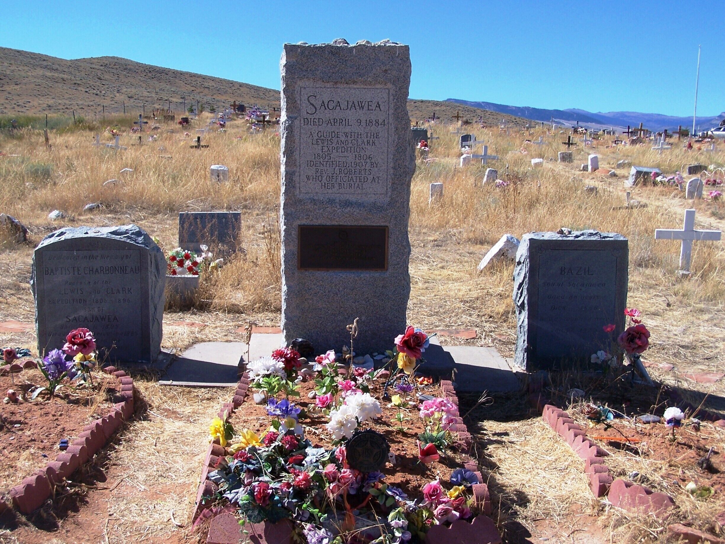 A cemetery with gravestones, including one for Sacajawea, adorned with colorful flowers.
