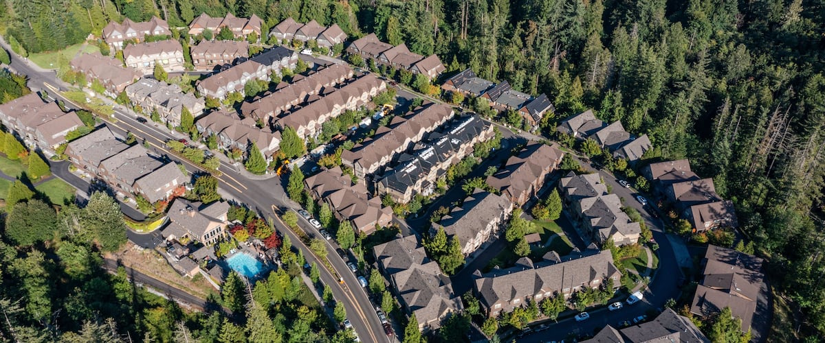 An aerial view of a residential area with houses, roads, and a swimming pool.