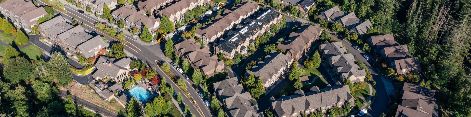 Vista aérea de una zona residencial con casas, calles y una piscina.