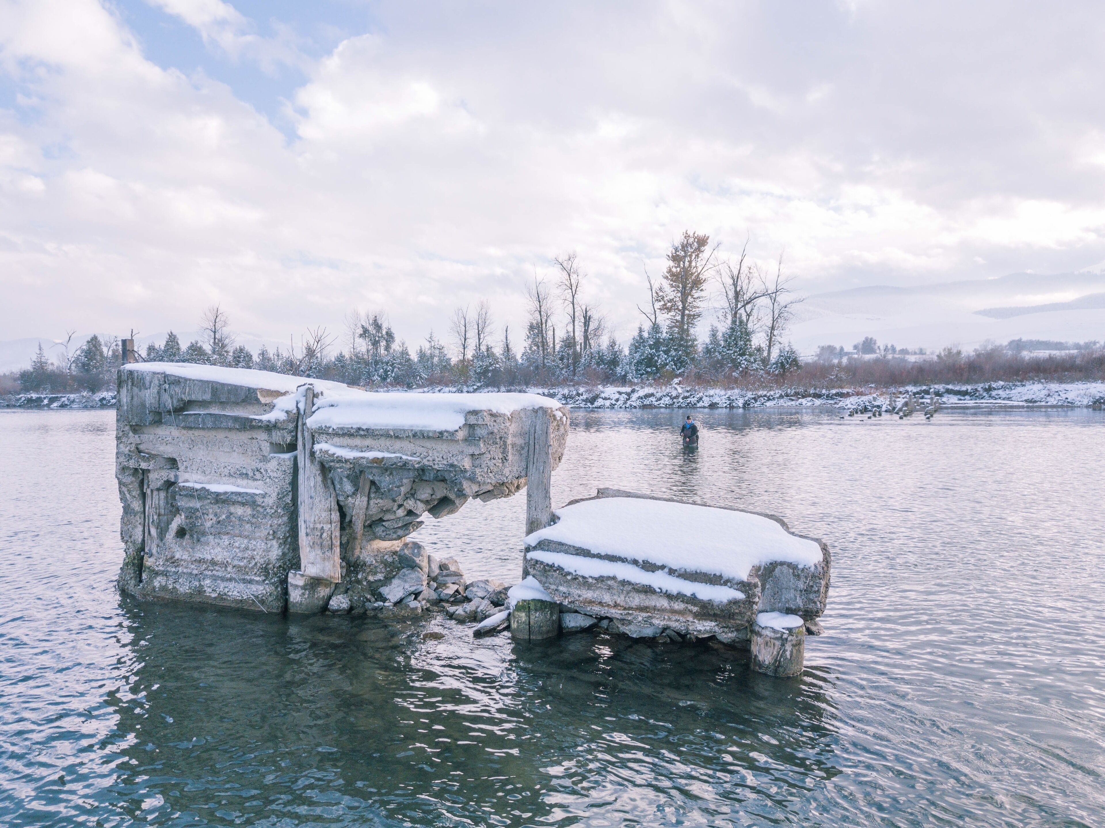 A frozen river with large ice formations and a person fishing.