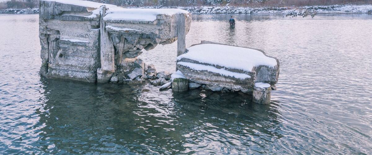 A frozen river with large ice formations and a person fishing.