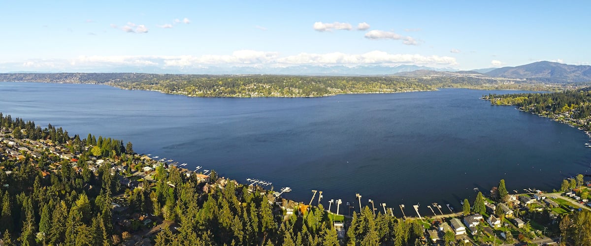 A large lake surrounded by dense forests and mountains in the background.