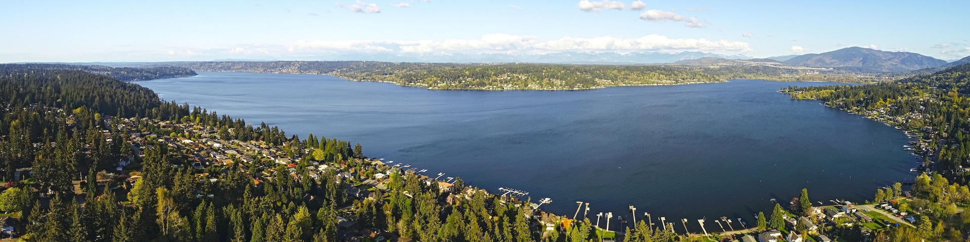 A large lake surrounded by dense forests and mountains in the background.