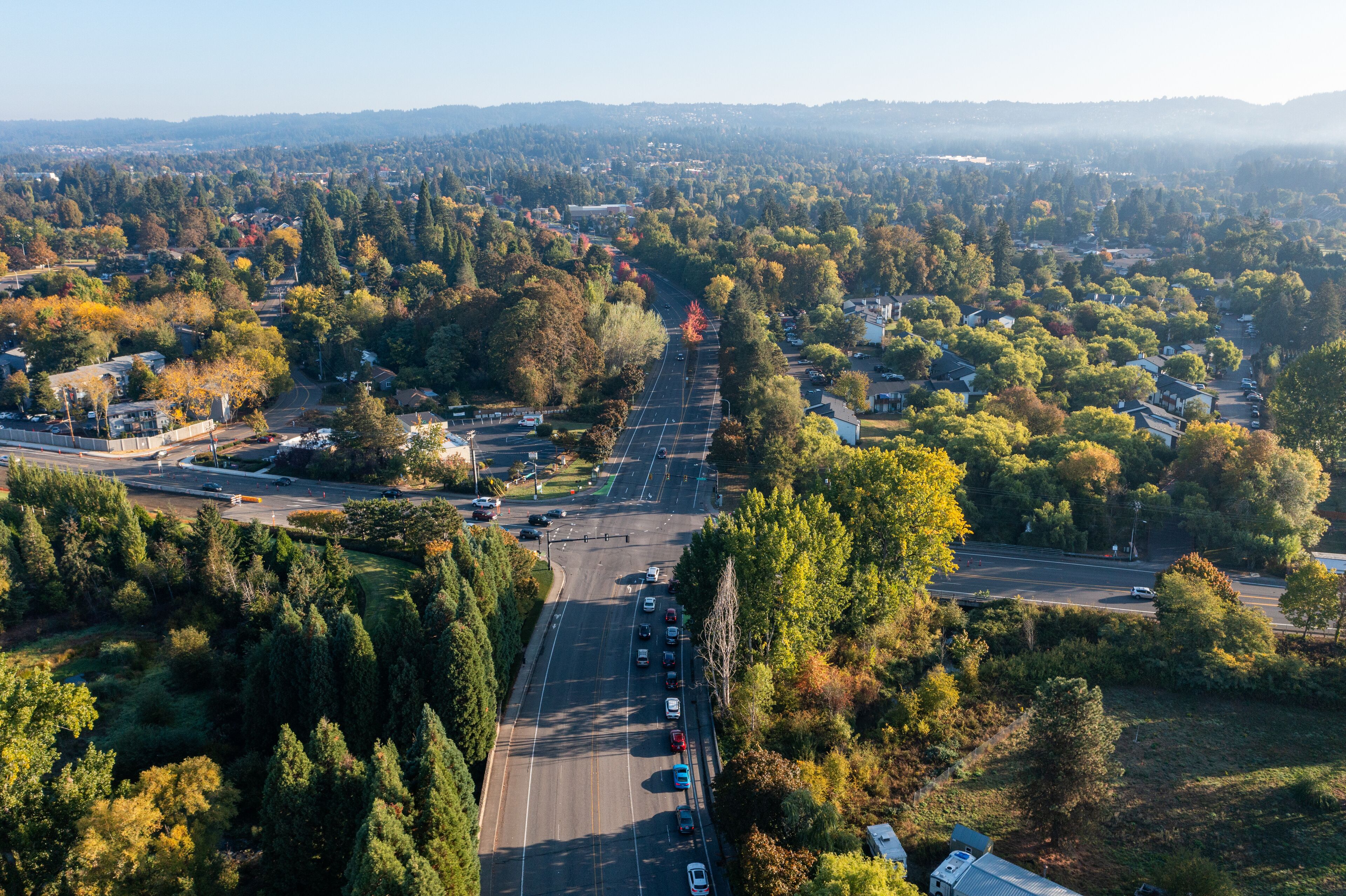 Aerial drone photo of an empty street with a fall autumn colors, trees, captured early morning at sunrise. No people
