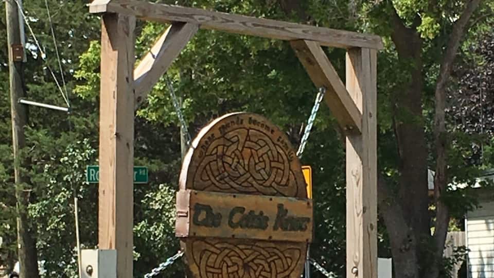 A wooden sign with a Celtic knot design and the text "The Celtic Knot" mounted on a metal frame.