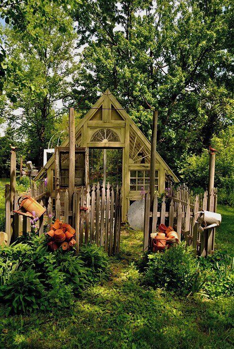 A rustic wooden garden structure surrounded by lush greenery and various gardening tools.