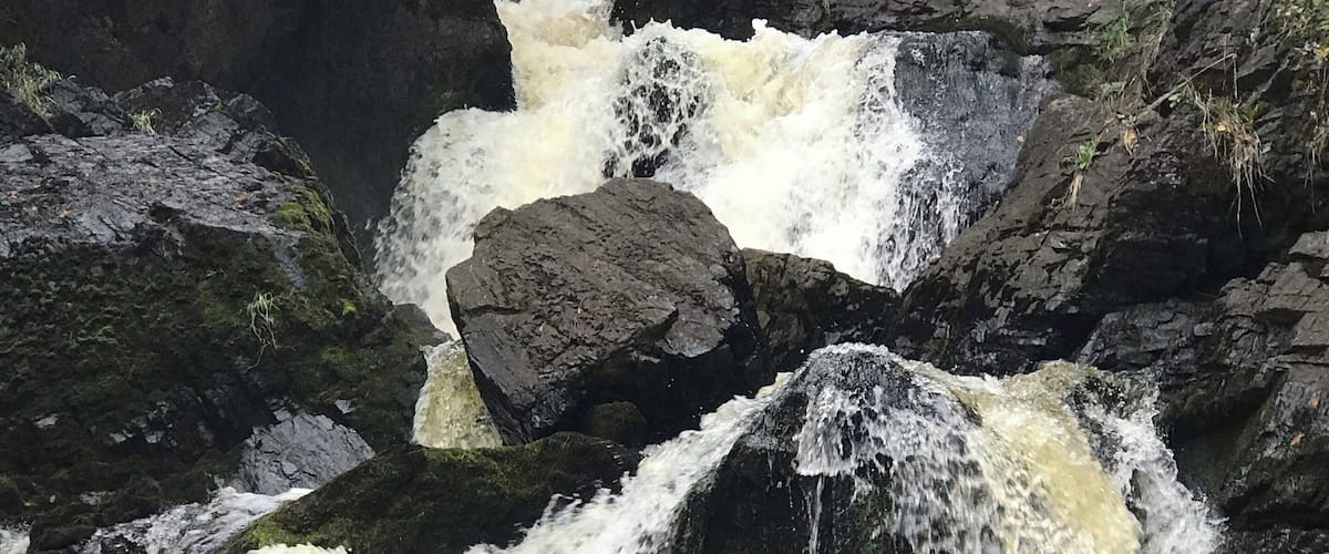 A waterfall cascading over rocks in a forested area.