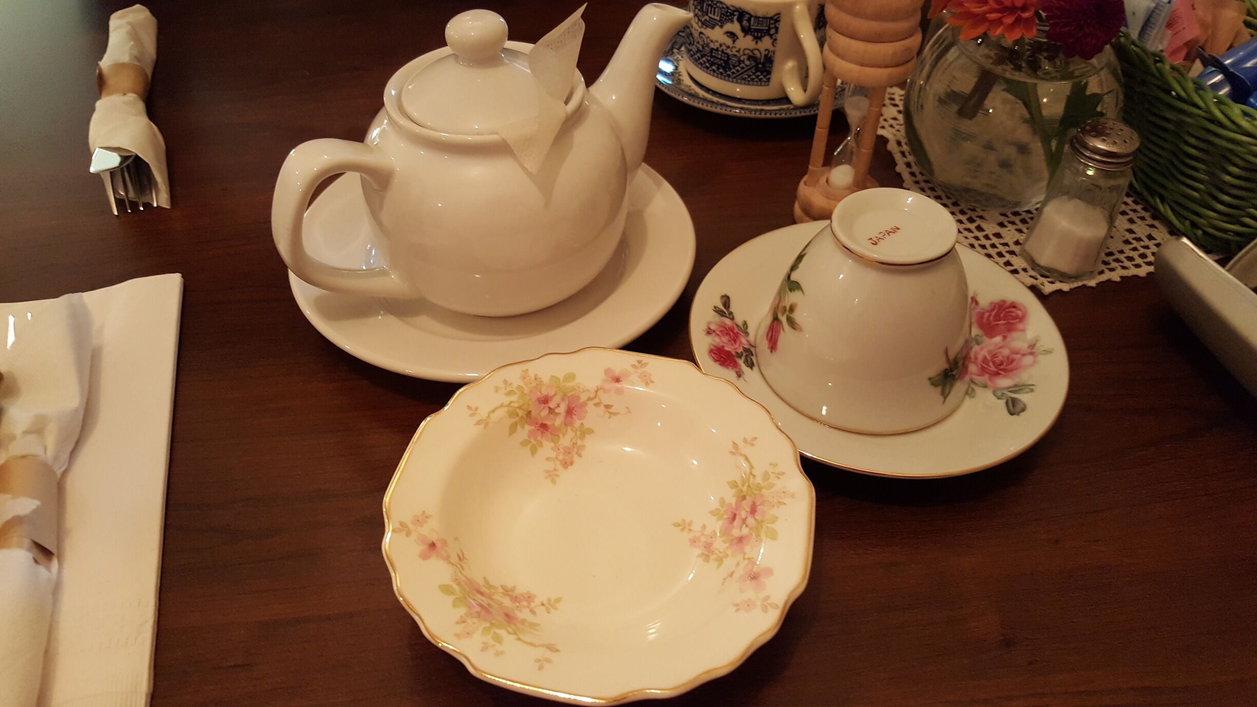 A tea set with floral patterns on plates and a teapot on a wooden table.