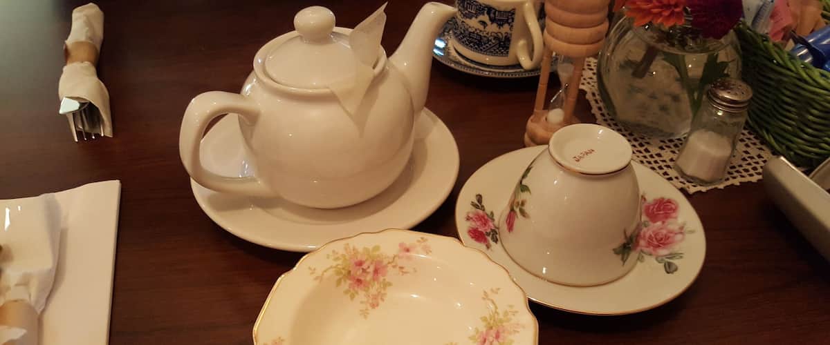 A tea set with floral patterns on plates and a teapot on a wooden table.