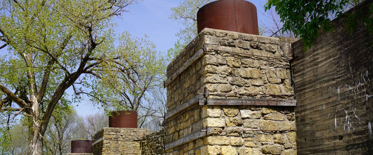 A stone building with a cylindrical chimney, surrounded by trees and grass.