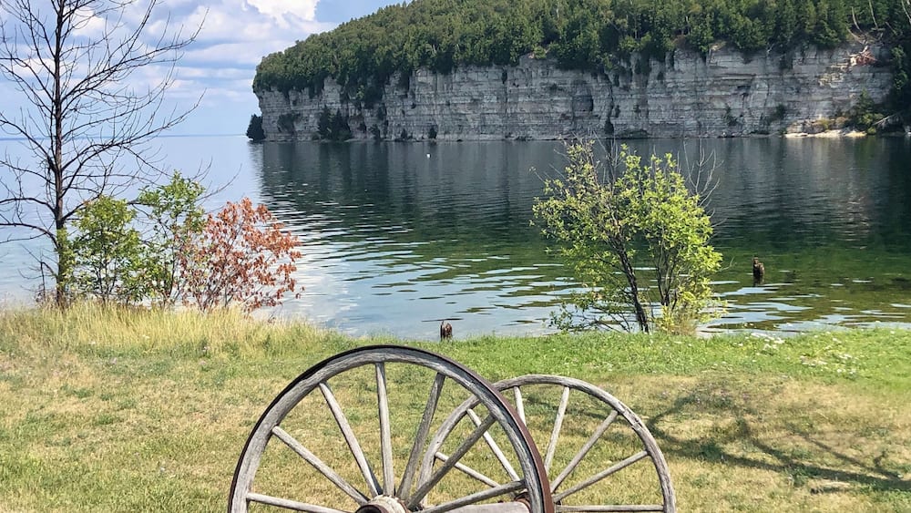 A lake with a cliff and a wooden cart.