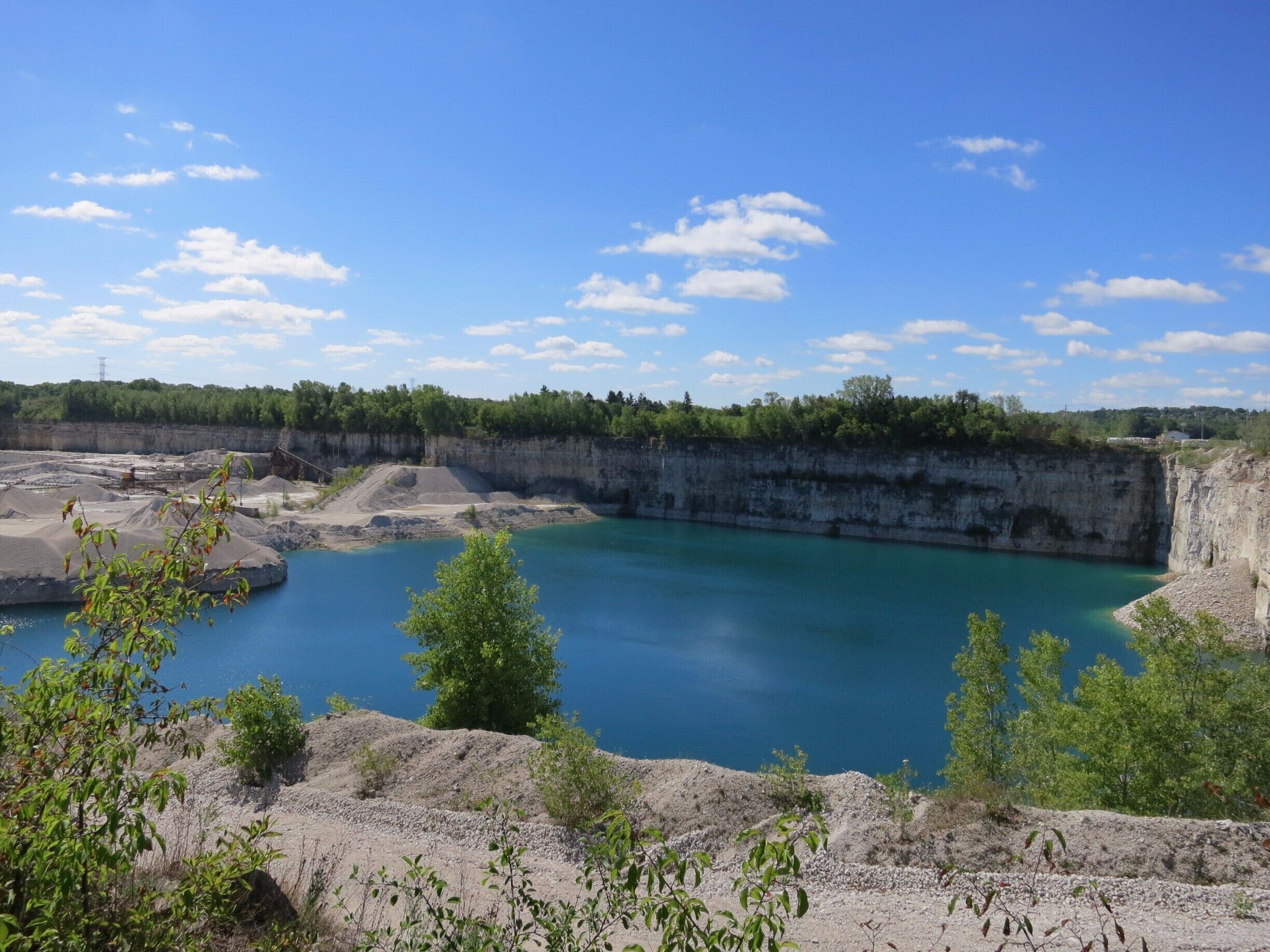 A quarry with a large water body and surrounding greenery.