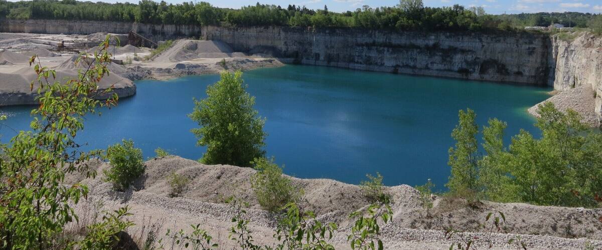 A quarry with a large water body and surrounding greenery.