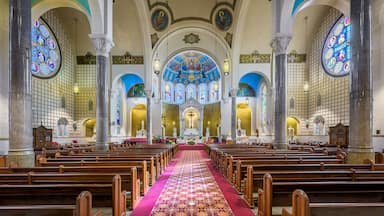 Interior de iglesia con bancas de madera, vidrieras y un altar central.
