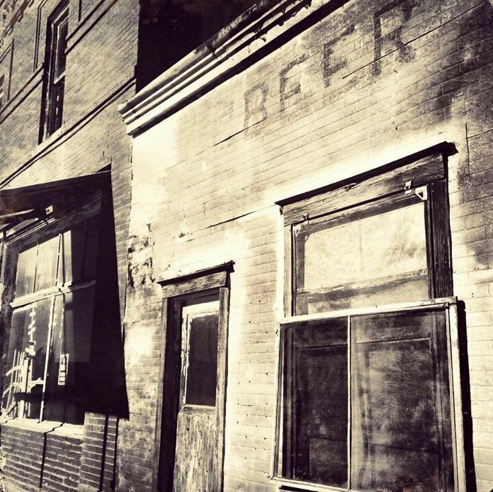 An old brick building with boarded-up windows and a weathered facade.