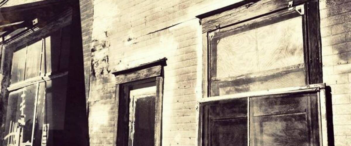 An old brick building with boarded-up windows and a weathered facade.