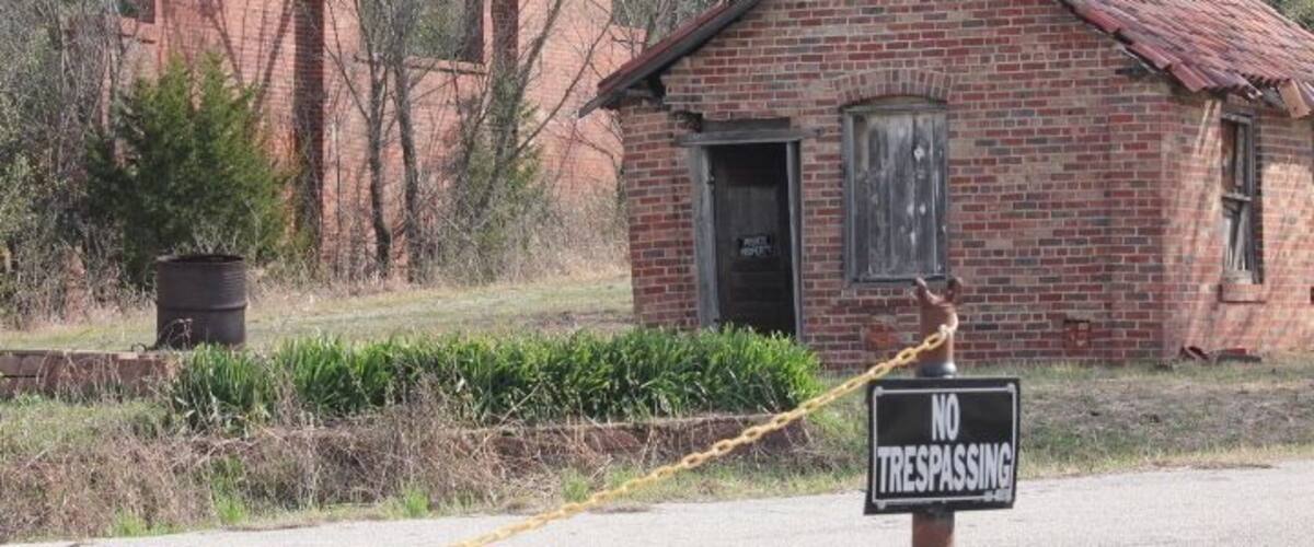 A small brick building with a 'NO TRESPASSING' sign in front.