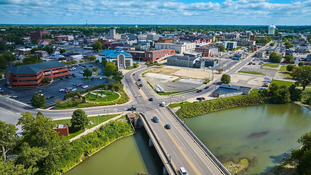 Aerial above White River N High Street bridge overlooking Muncie, IN downtown city buildings