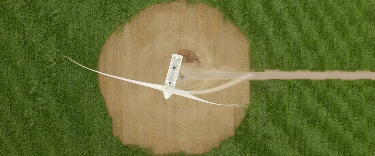 An aerial view of a wind turbine on a grassy field.