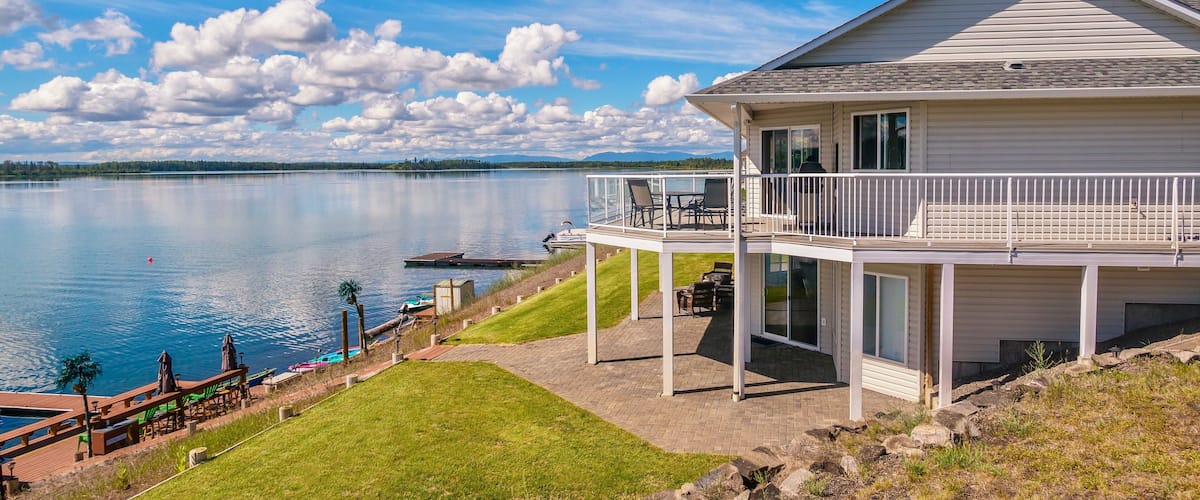 A lakeside house with a balcony overlooking the water.