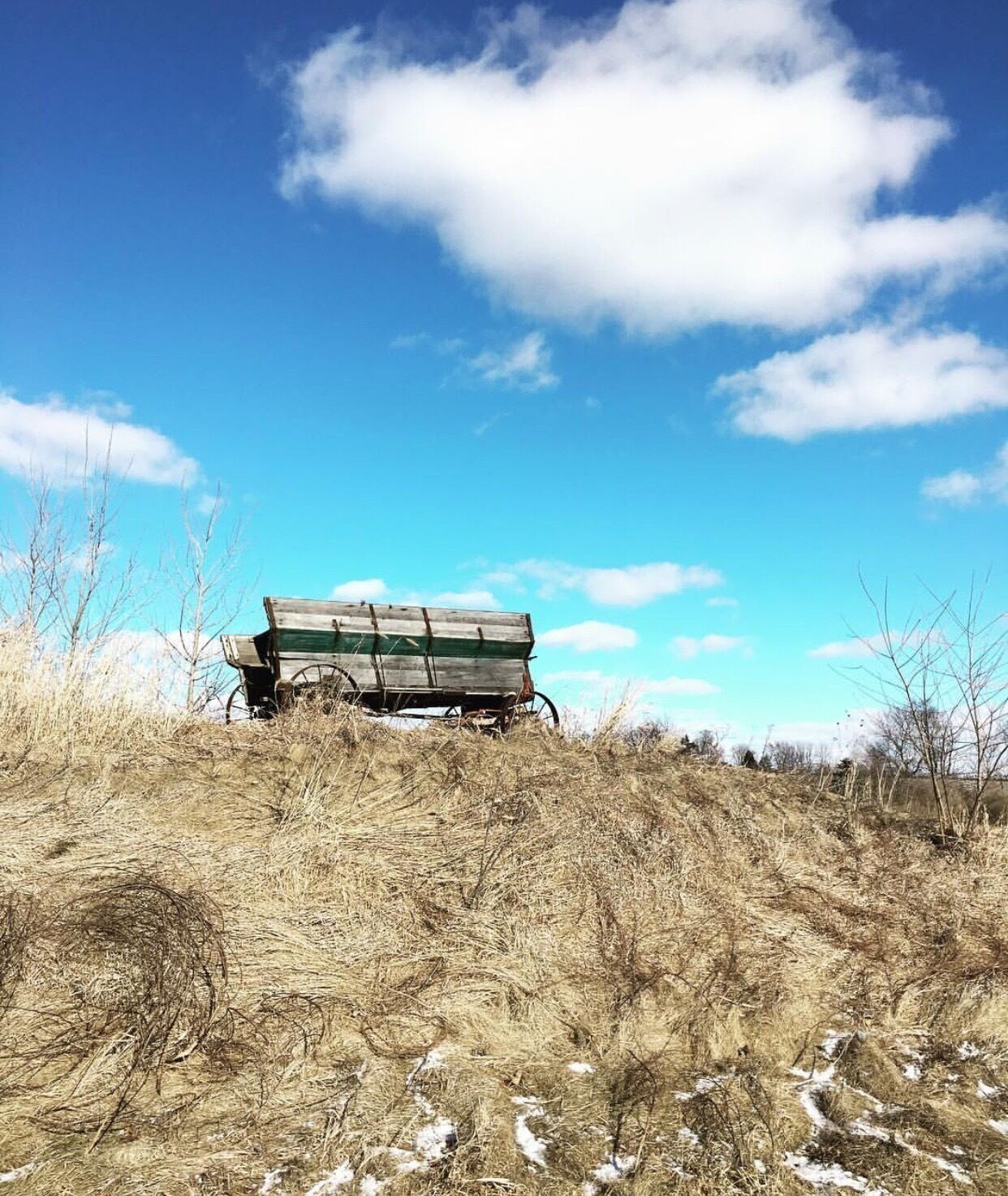 A wooden cart on a grassy hill with a clear blue sky.