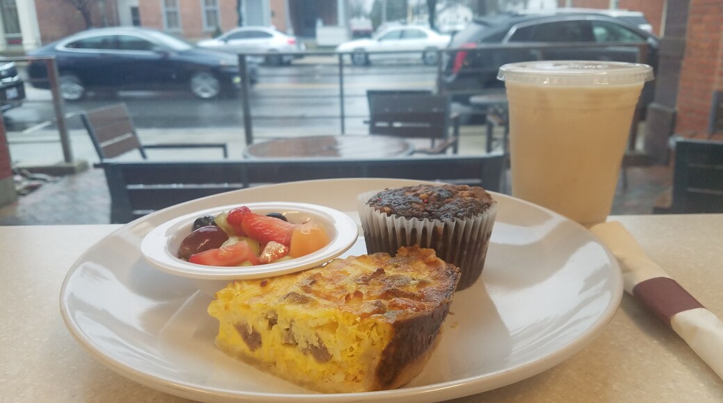 A view from inside looking out to the patio and street beyond.
The food on the plate is a slice of their Sausage & Bacon Quiche, bowl of fresh fruit, and the Chocolate Reeses Muffin. Also photographed is the medium size of an Iced Chai Tea Latte.
