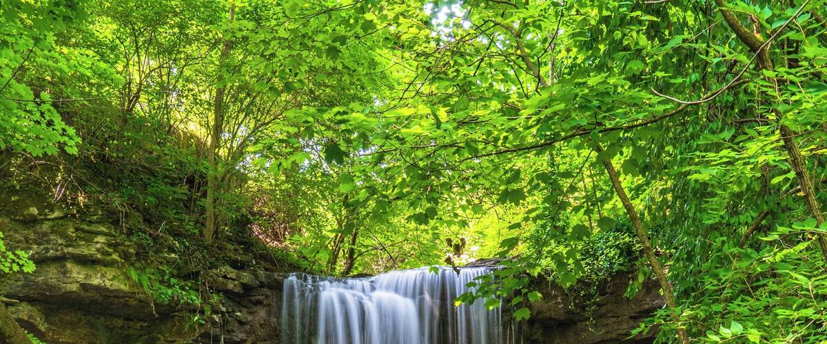 A multi-tiered waterfall surrounded by lush greenery.