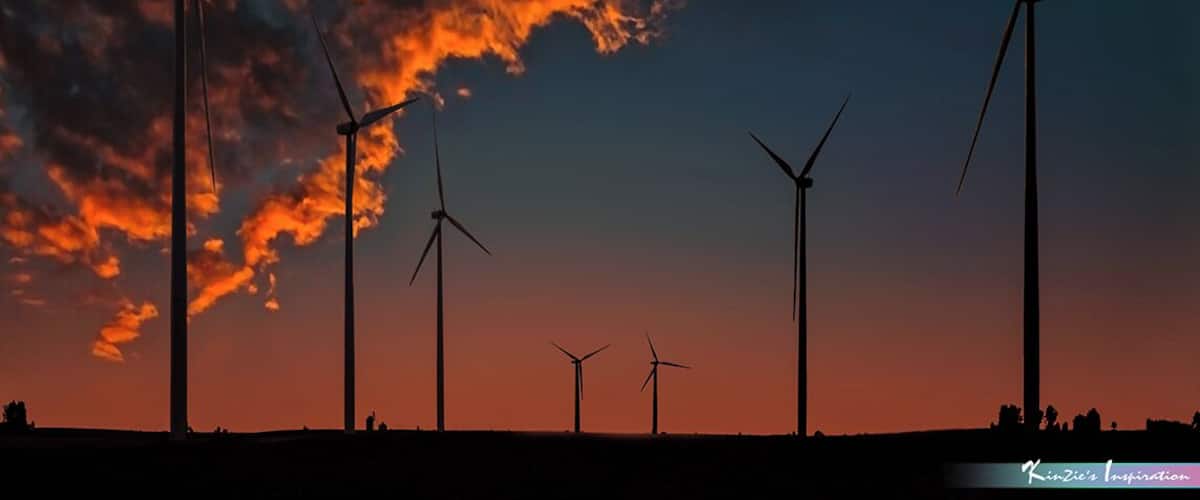 A silhouette of wind turbines against a sunset sky.