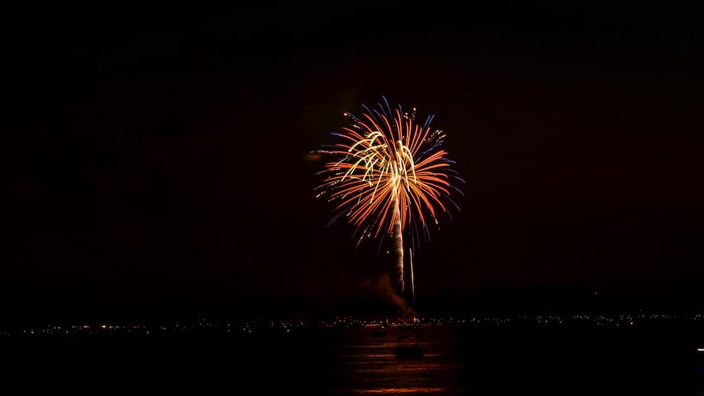 Ein Nachthimmel mit einem Feuerwerk über einem Gewässer.