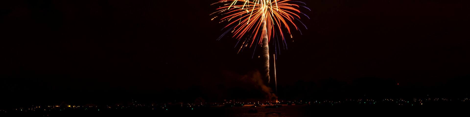 A night sky with a firework display over a body of water.