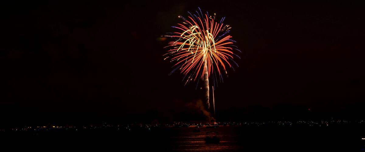 A night sky with a firework display over a body of water.