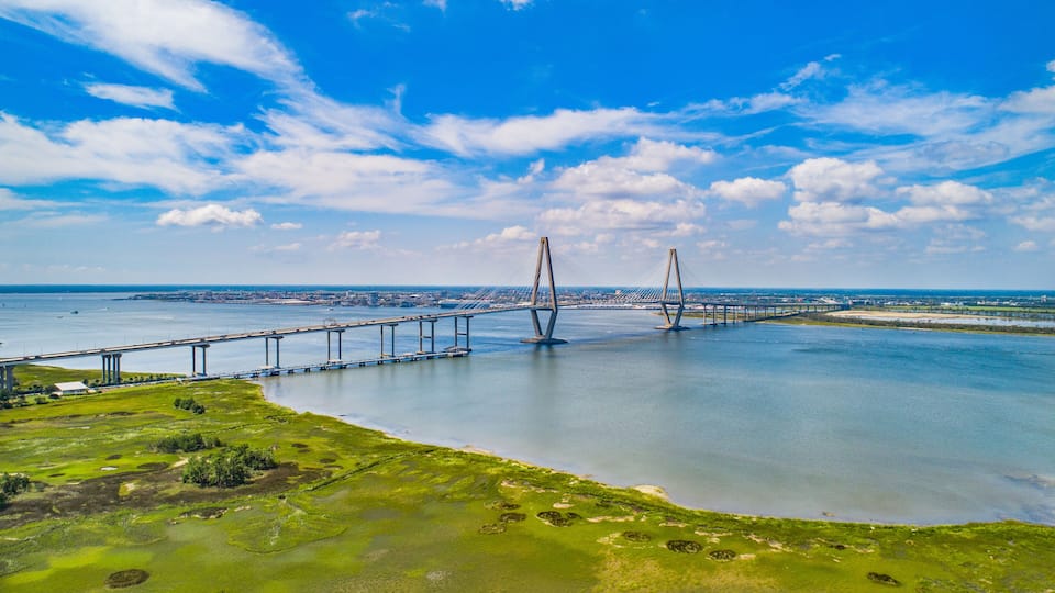 A cable-stayed bridge over a body of water with a cityscape in the background.