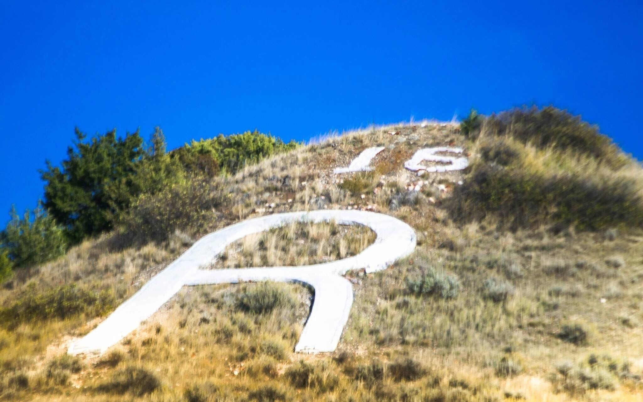 A winding road on a grassy hill with a clear blue sky.