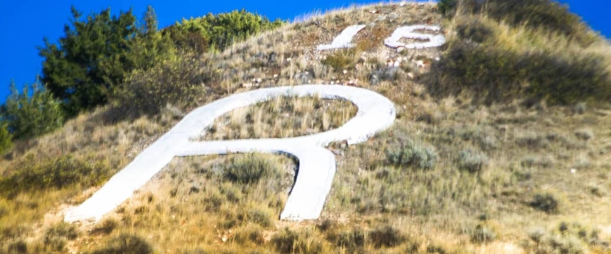 A winding road on a grassy hill with a clear blue sky.