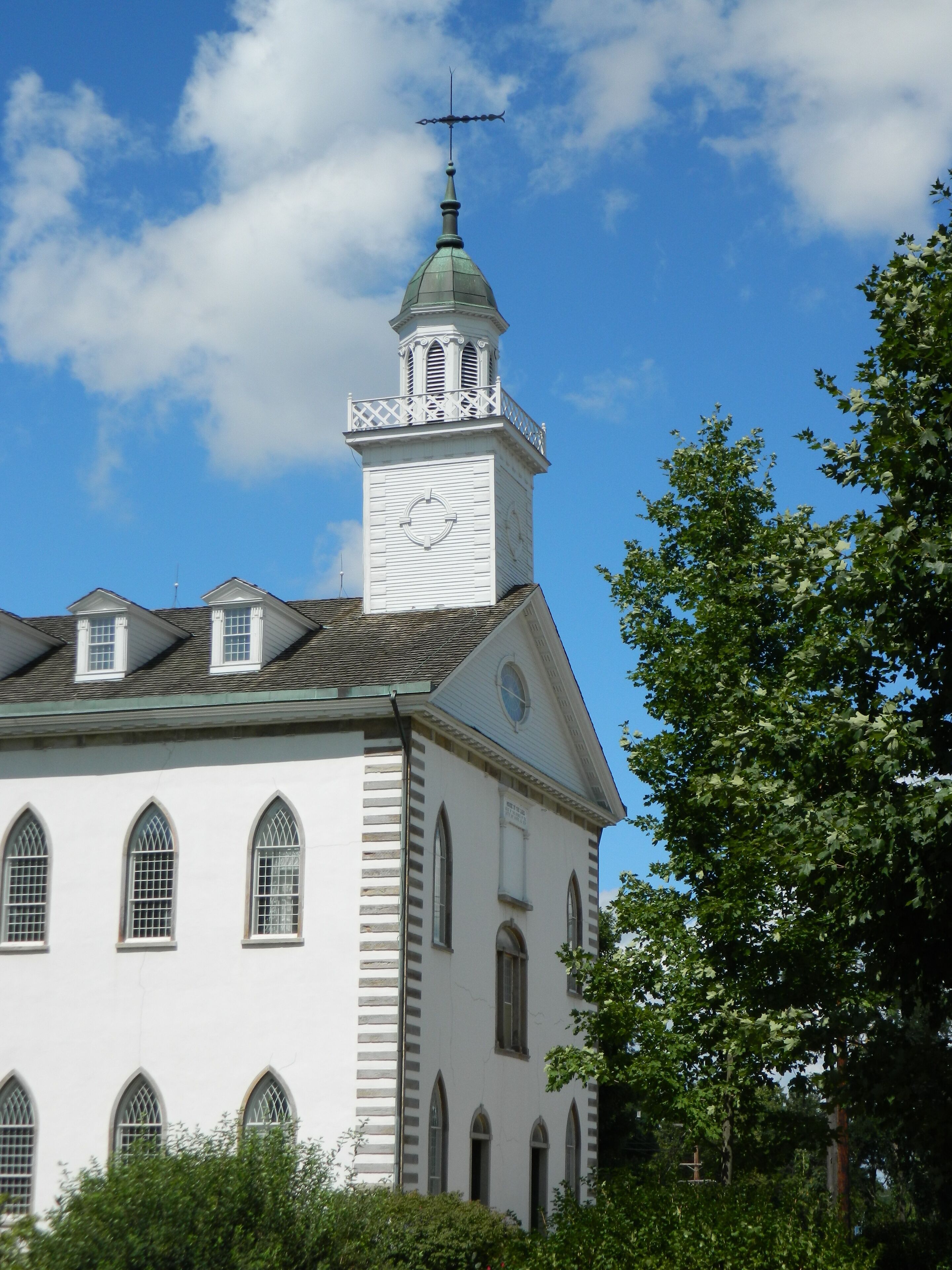 A white church with a steeple and a clock tower.