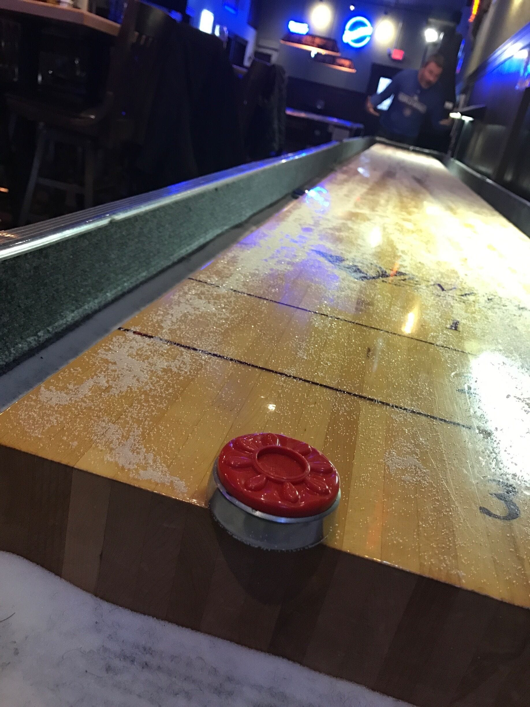 A shuffleboard table with a red puck in the center.