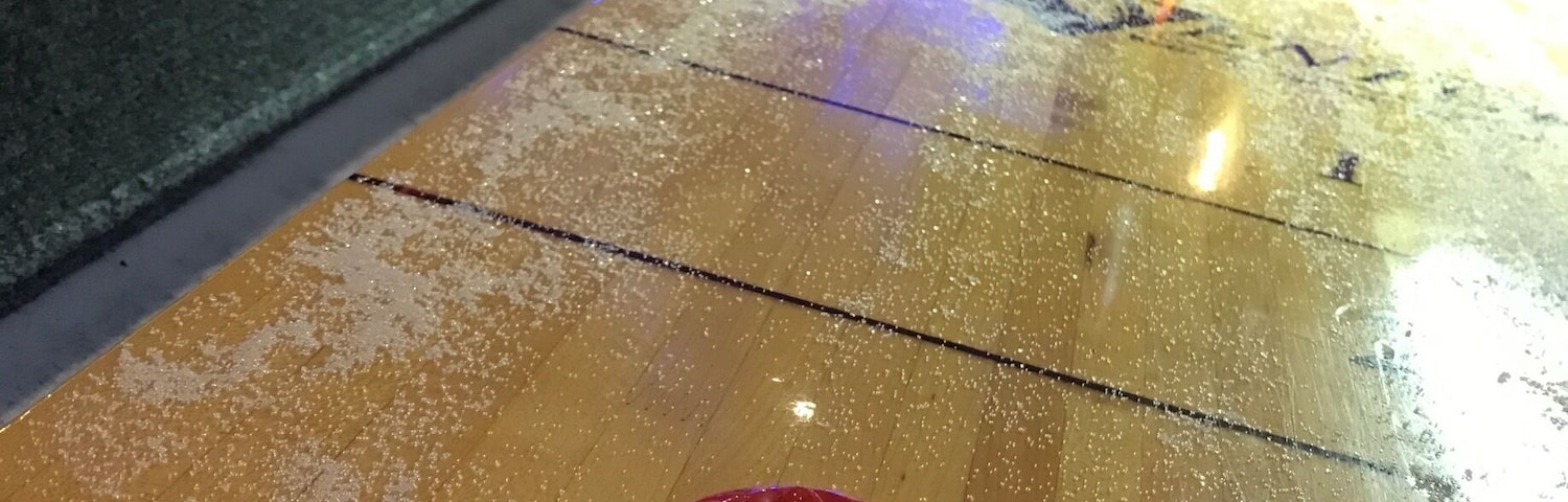 A shuffleboard table with a red puck in the center.