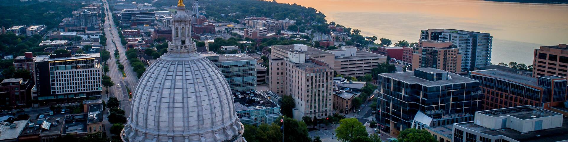 A cityscape with a prominent dome building, a river, and a sunset.
