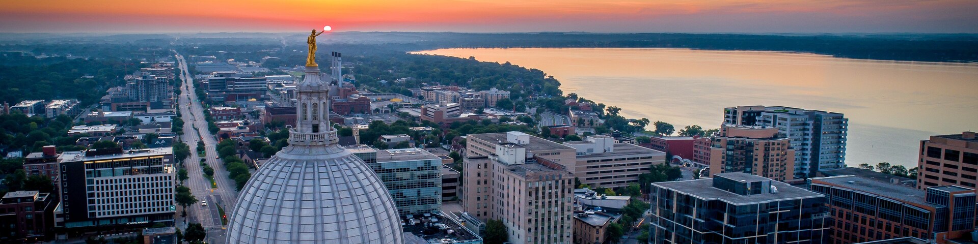 A cityscape with a prominent dome building, a river, and a sunset.