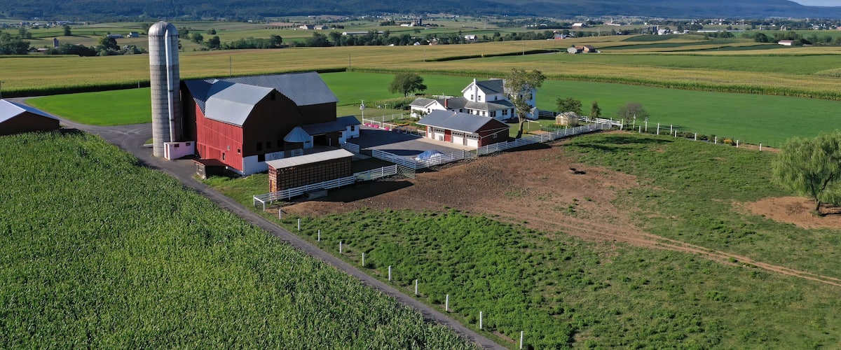 A farm with barns, a silo, and green fields.