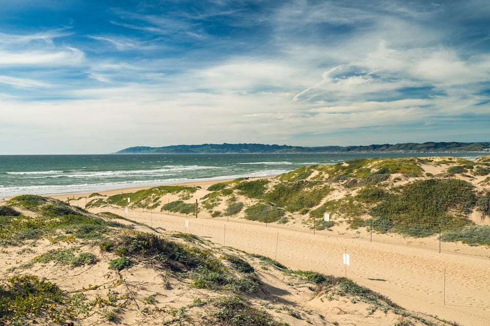 Una platja sorrenca amb dunes i un cel serè.